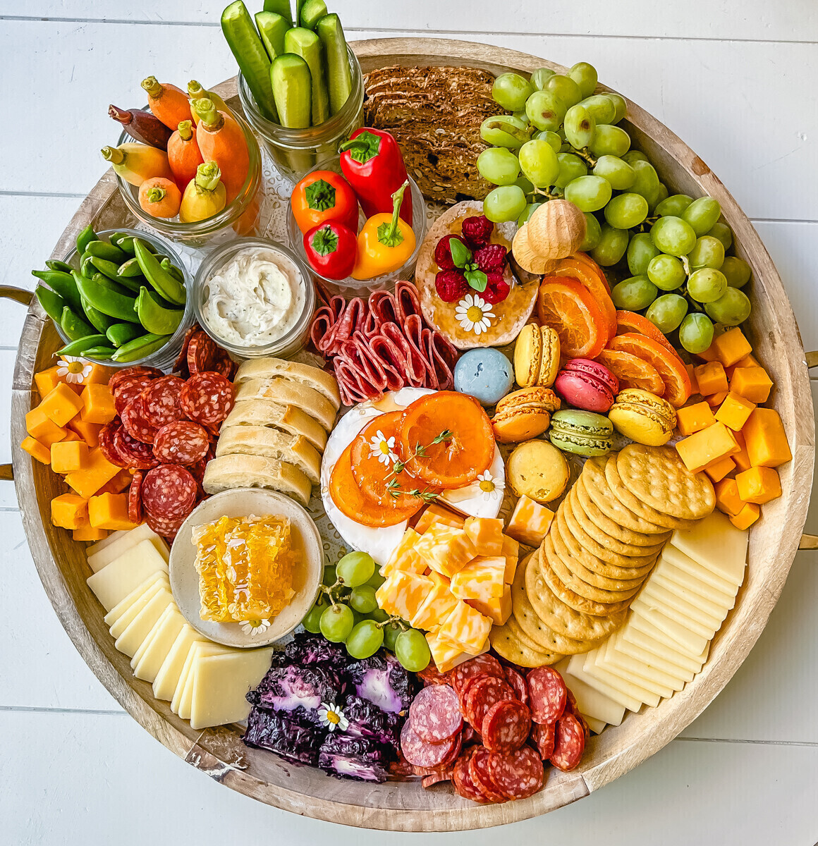 Round snack board with meat, cheese, crackers and other colourful snack